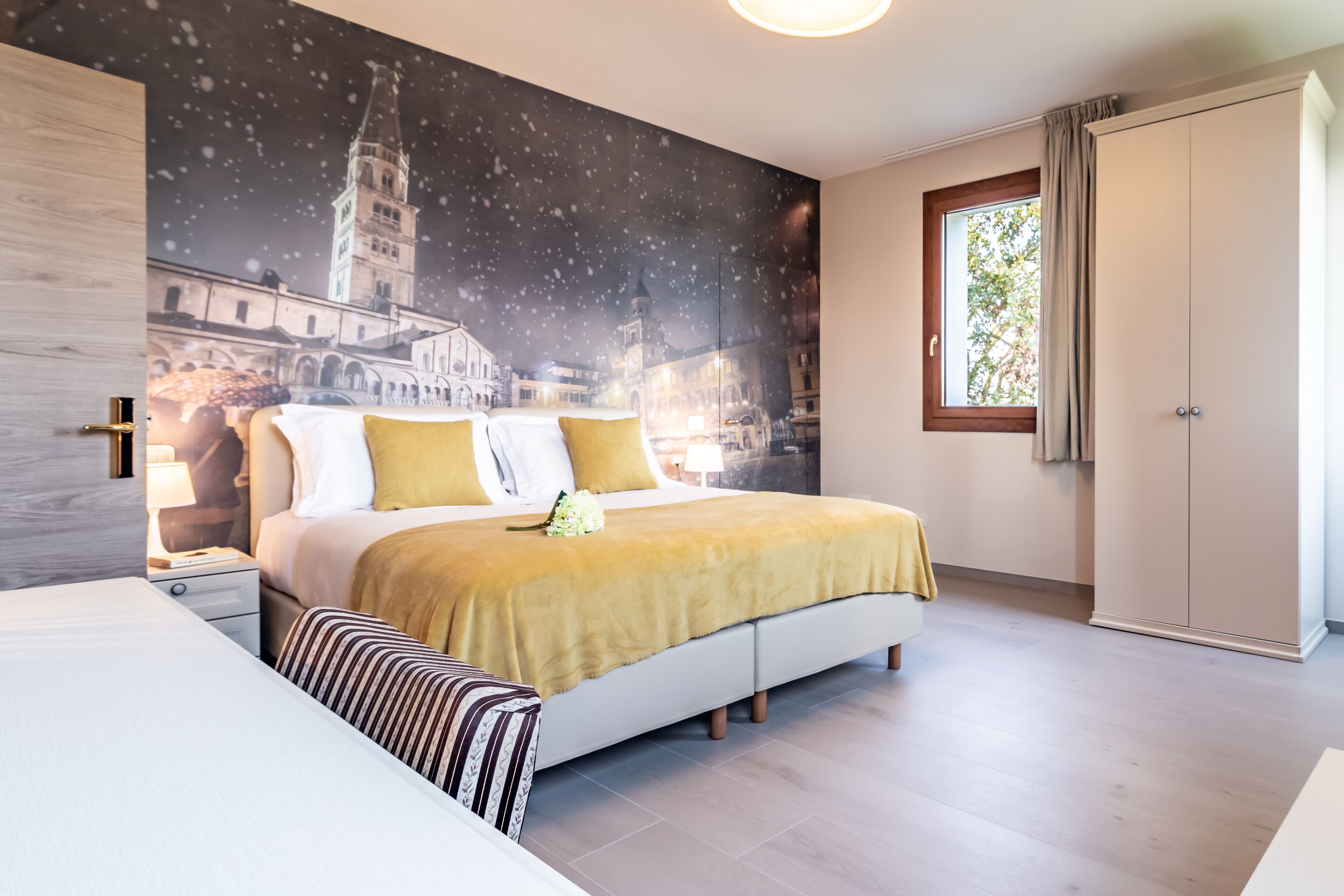 Un dormitorio moderno con una cama grande, una mesita de noche, un banco y un armario.