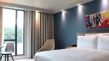 Een hotelkamer met een groot bed, een stoel, een bureau en een raam met gordijnen.
