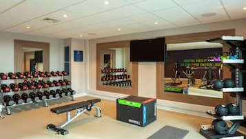 A gym with weightlifting equipment, a bench, and a mirror.
