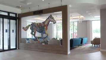 A reception area with a colorful horse sculpture, a wooden reception desk, and modern seating.