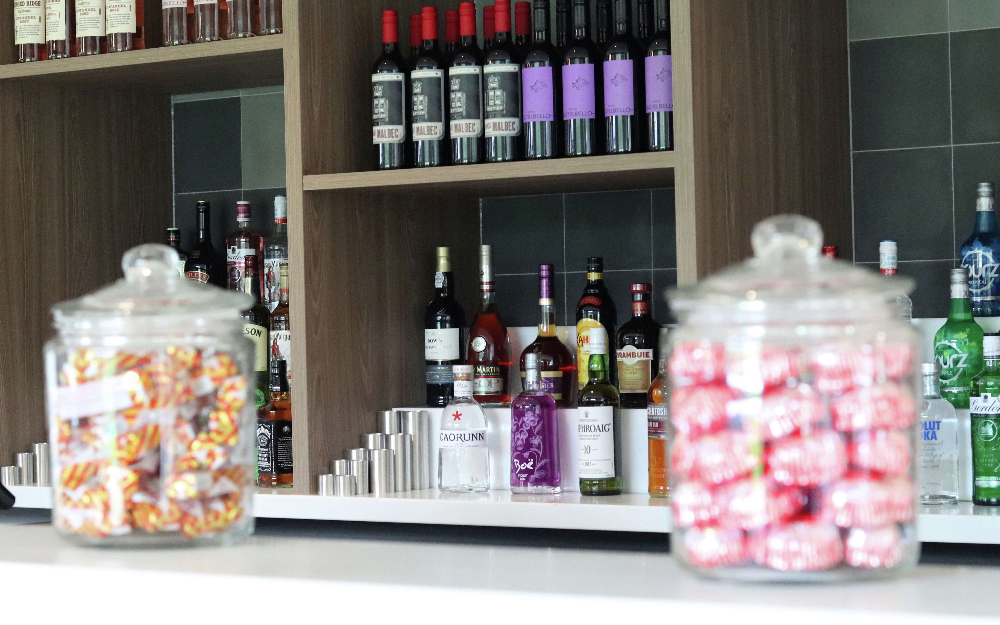 A liquor store shelf with various bottles and jars of alcohol.