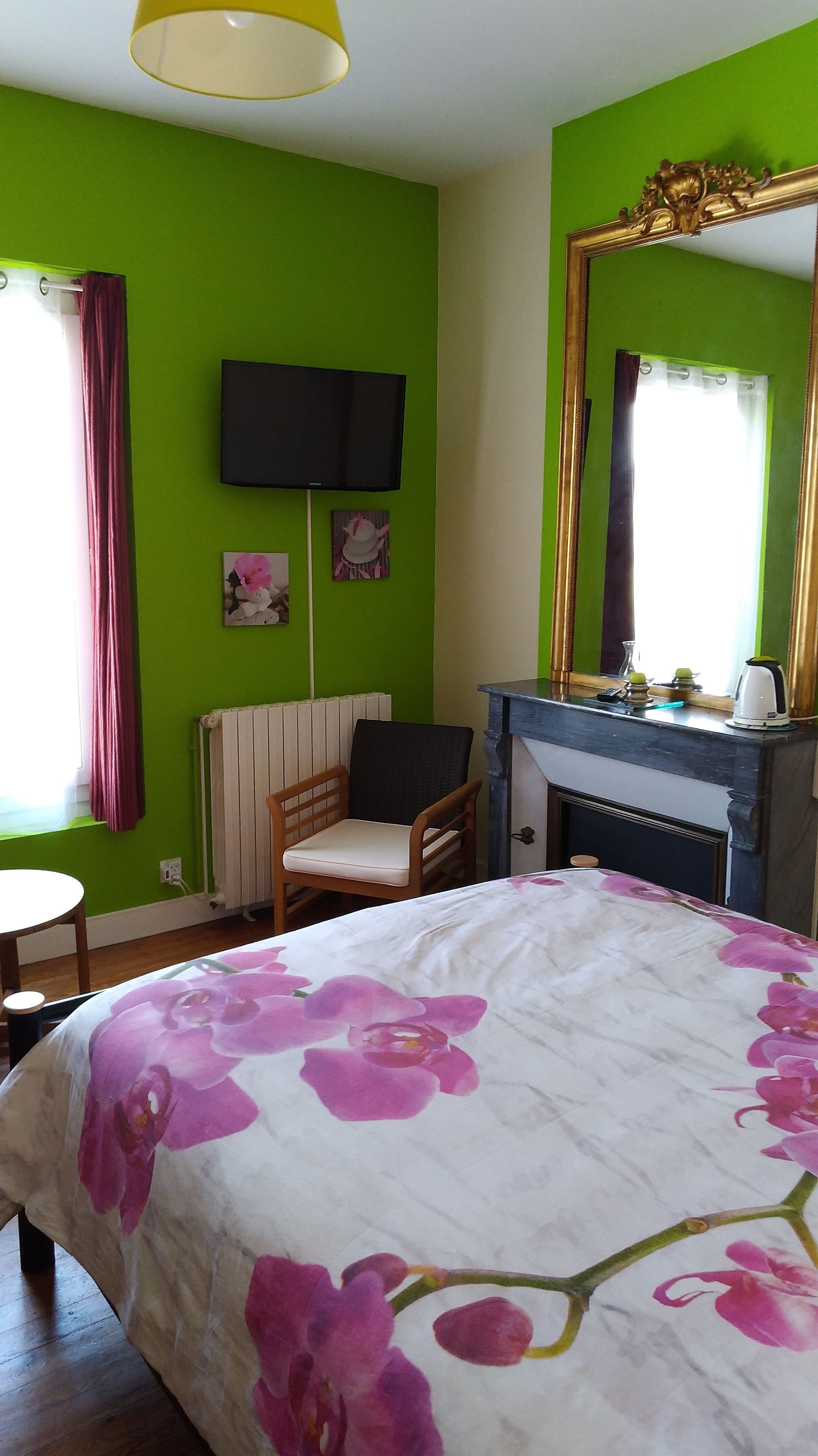Ein Schlafzimmer mit einem Bett, einem Sessel, einem Fernseher, einem Kamin und einem Spiegel.