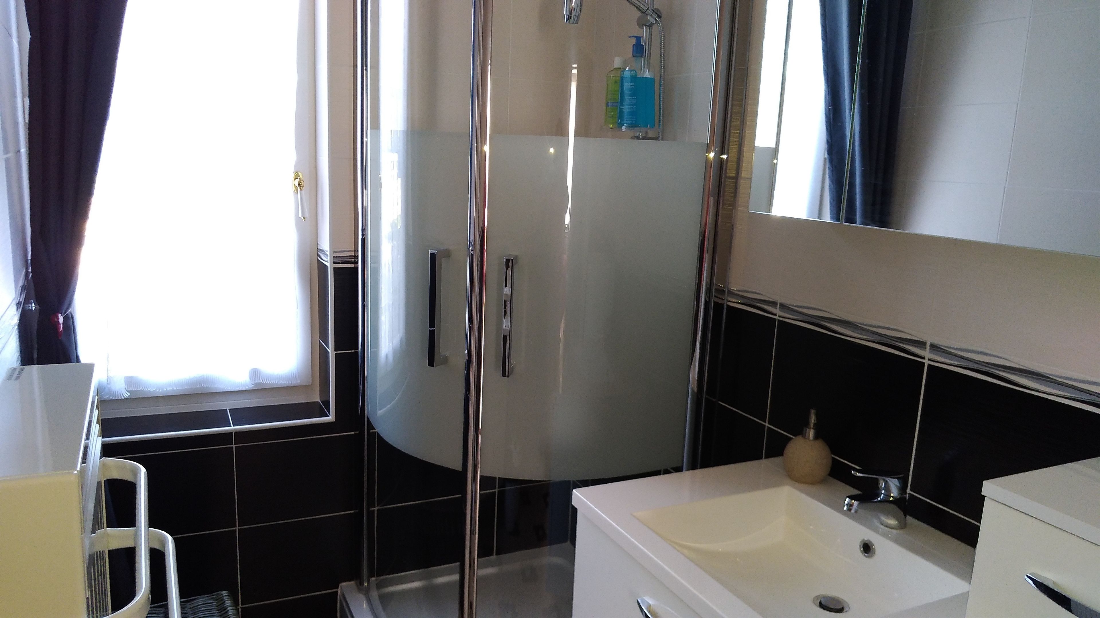 Un baño moderno con cabina de ducha de vidrio, un lavabo blanco y un espejo sobre él.