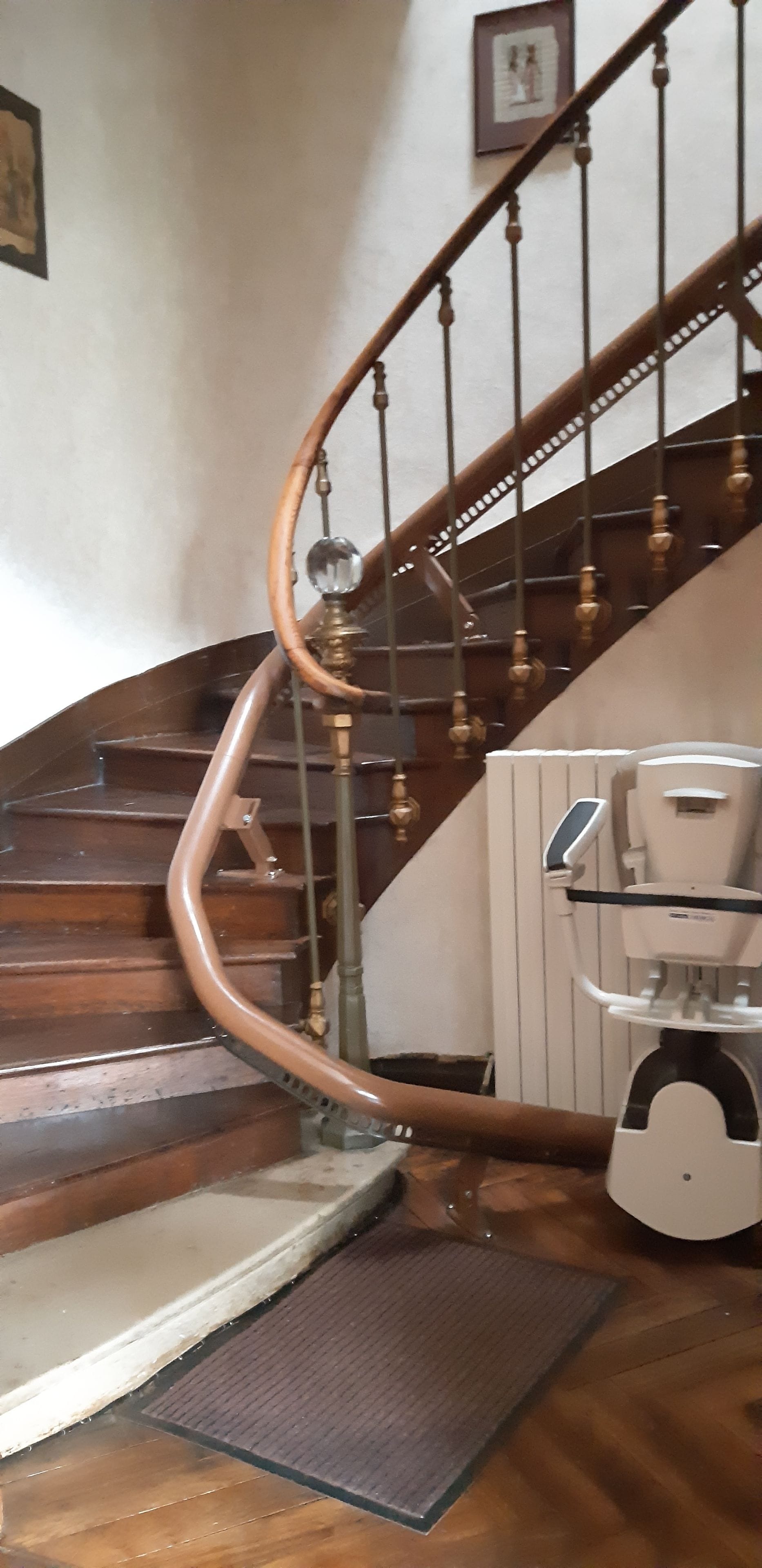 Un escalier en bois avec une rampe courbée et, au bas de l’escalier, une machine à café moderne.