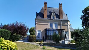 A two-story house with a large bay window, a chimney, and a well-maintained garden. - Chambres d'Hôtes Les Clefs du Bonheur (Chateau-Gontier)