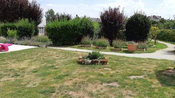 A garden with a gravel path, wooden planters, and a pink chair.