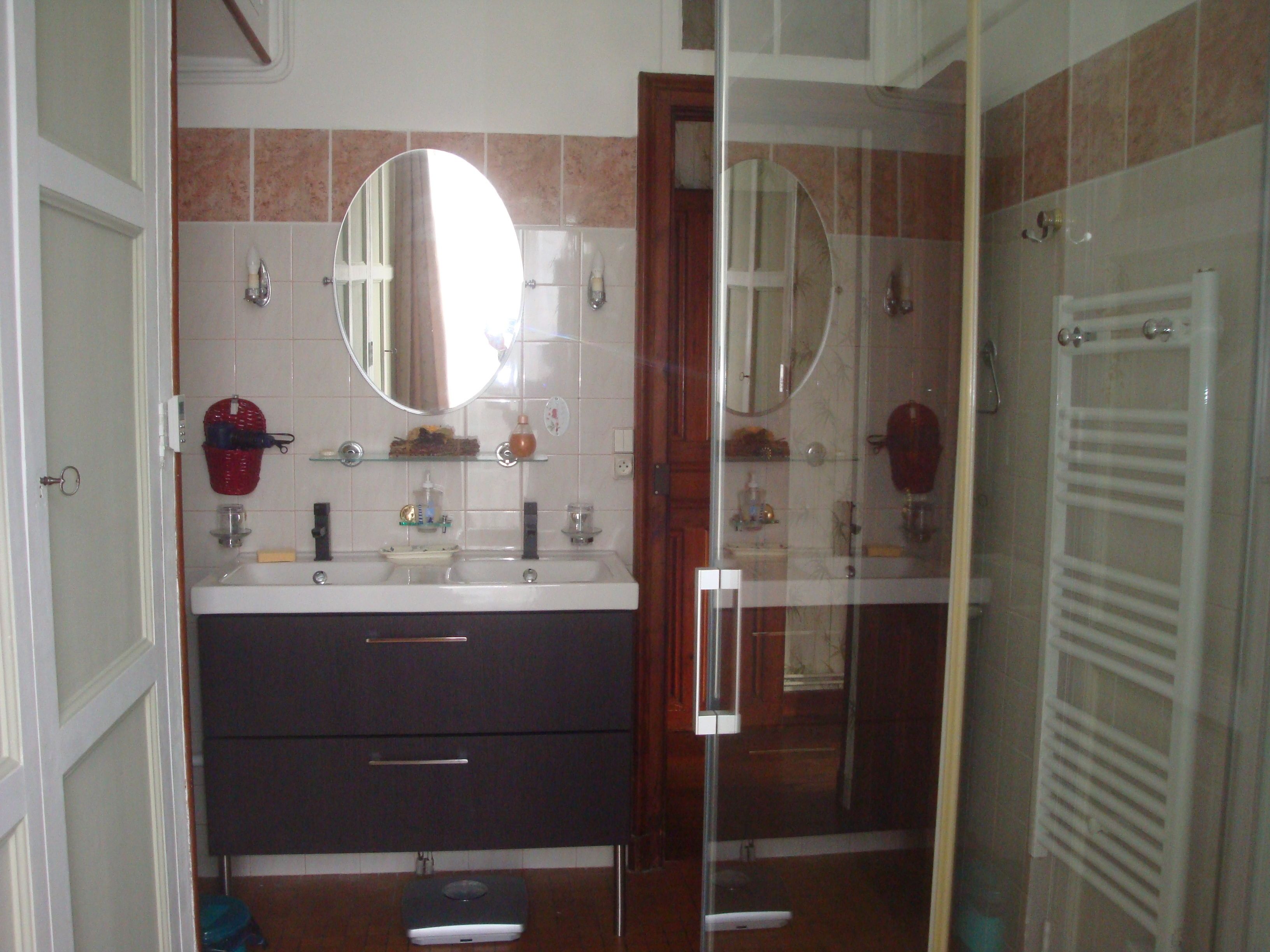 Een badkamer met twee wastafels, een spiegel, een handdoekhouder en een douche.