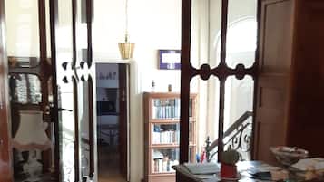 A room with a wooden floor, a dining table with chairs, a chandelier, and a bookshelf.