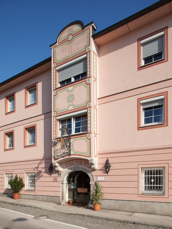 A pink building with a sign reading 'HOTEL SCHLAR' and a number '16' on the facade.