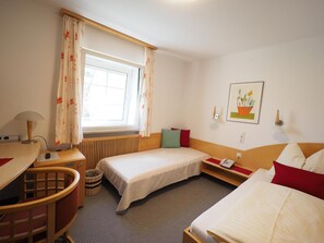 A hotel room with a bed, a desk, a chair, a telephone, and a window with curtains. - Hotel Schlair (Kremsmuenster)