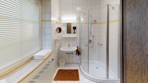 A modern bathroom with a glass-enclosed shower, a sink, and a toilet.