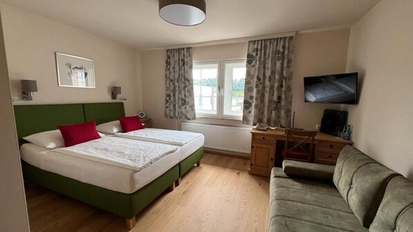 A hotel room with two beds, a desk, a television, and a sofa. - Hotel Schlair (Kremsmuenster)