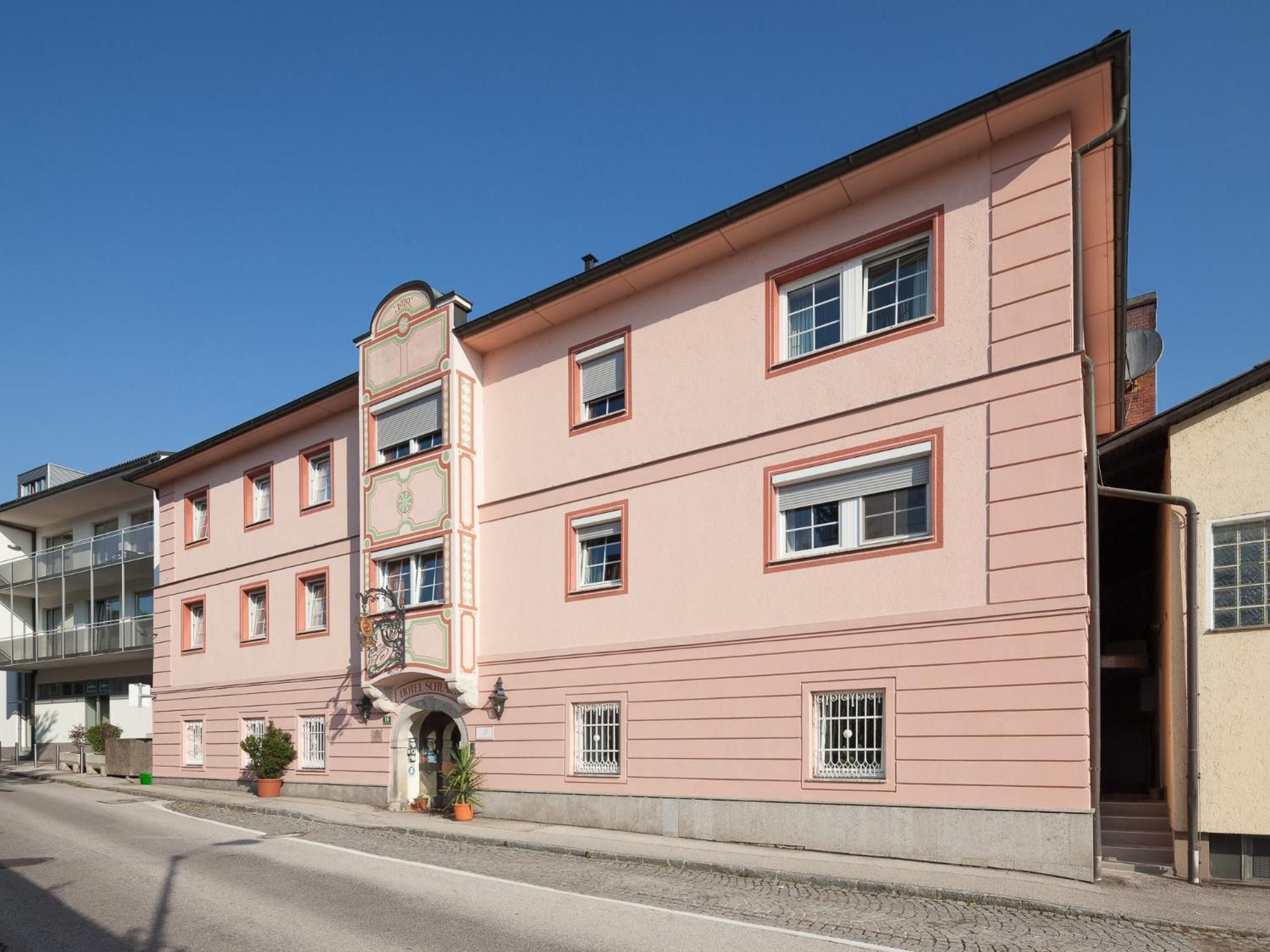 A pink building with multiple windows and a visible entrance.