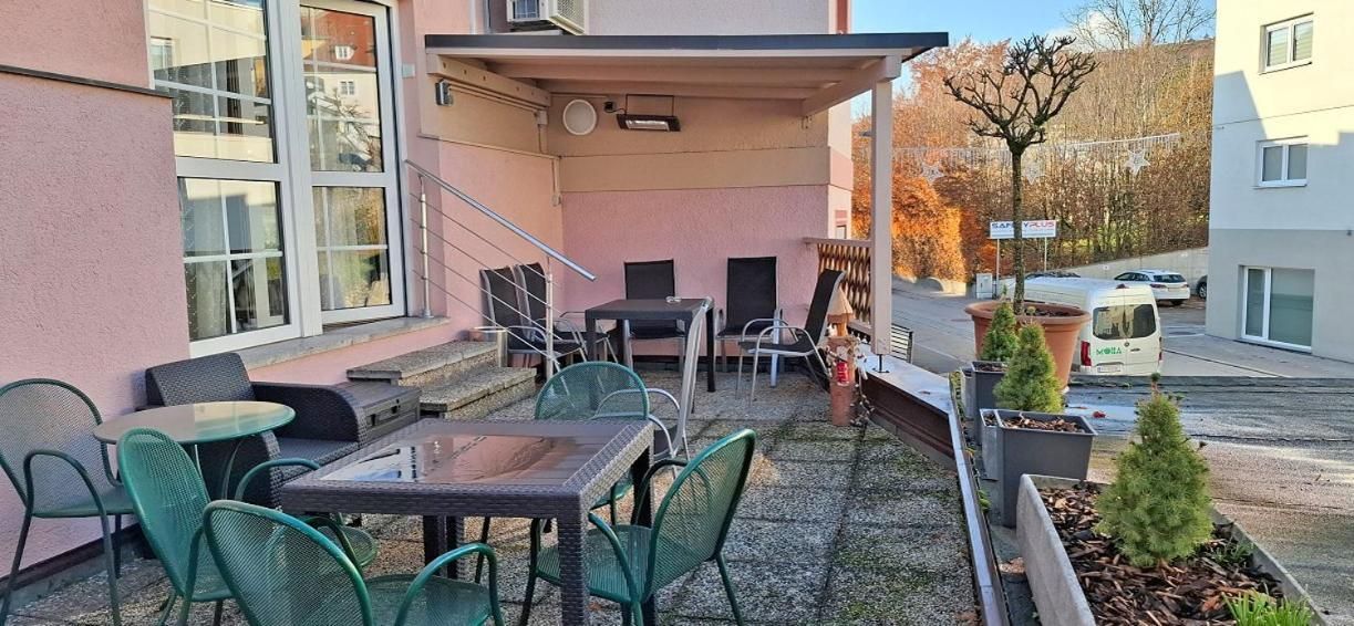 Eine Terrasse im Freien mit Tischen und Stühlen, einer kleinen Sitzecke und Topfpflanzen.
