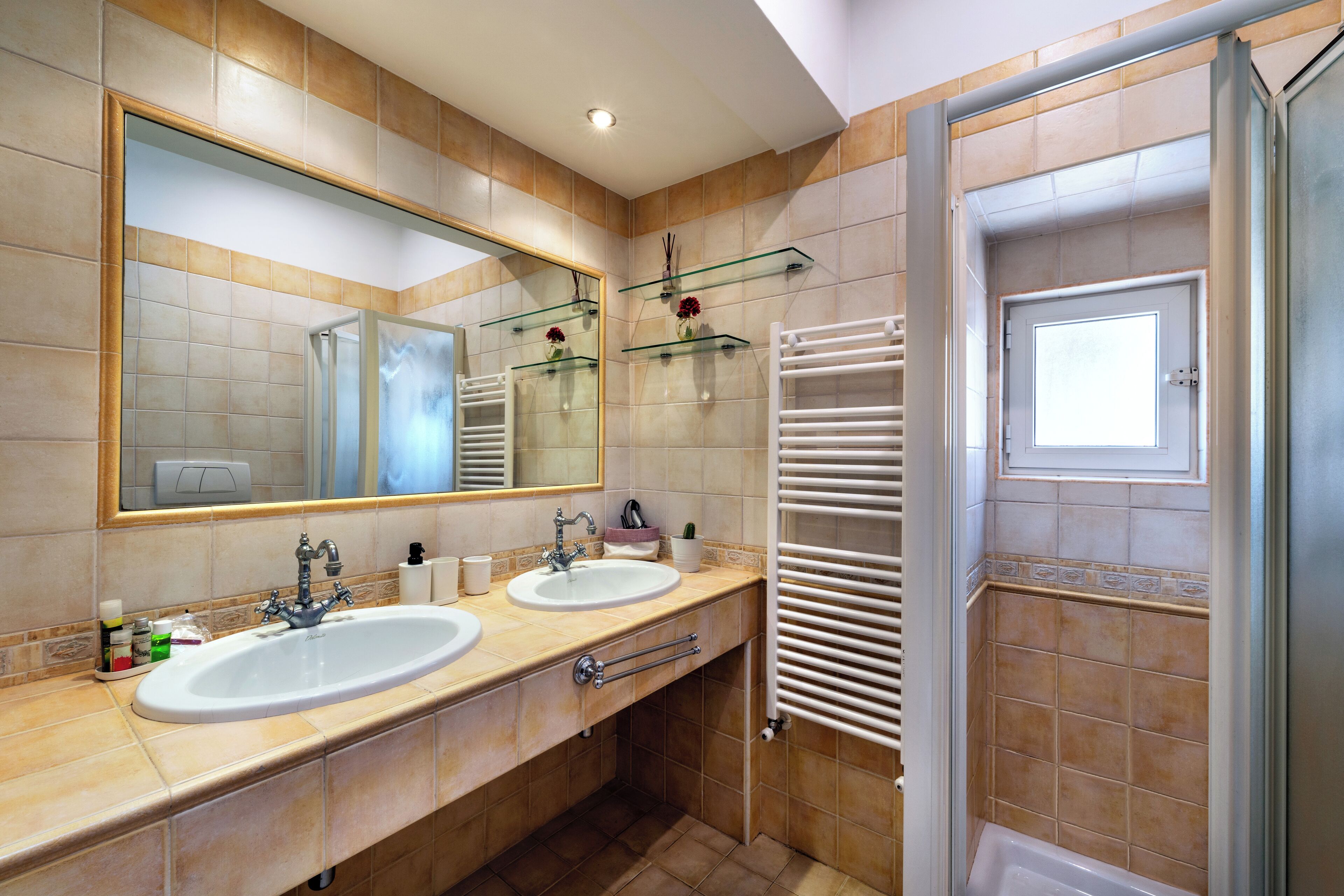 A modern bathroom with two sinks, a large mirror, and a glass shower enclosure.