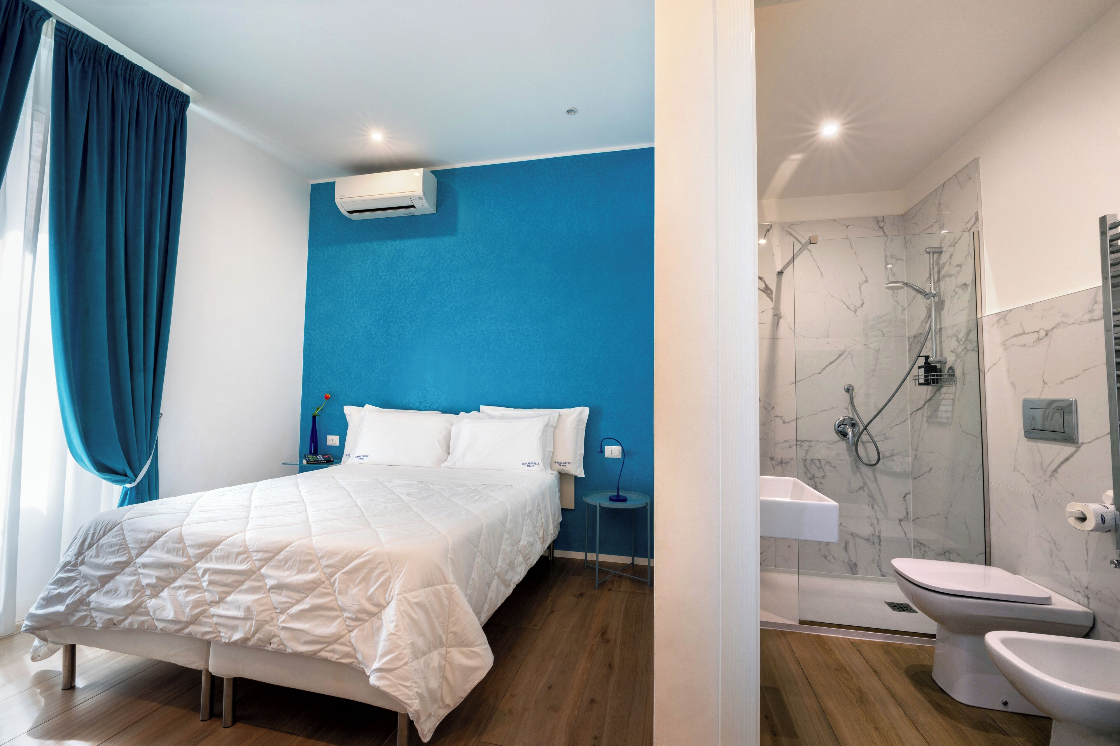 A modern bedroom with a large bed, a bedside table, and a nightstand.
