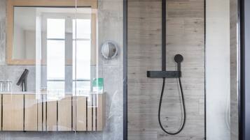 Une salle de bain moderne avec une douche à parois de verre, un meuble-lavabo en bois et un grand miroir.