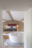 Un dormitorio moderno con una bañera blanca grande, techo de madera y cabecera roja.