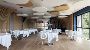 A modern dining area with round tables, white chairs, and a wooden floor. -  Hôtel & Restaurant Origines par Adrien Descouls - Teritoria (Le Broc)