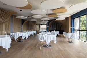 Un comedor moderno con mesas redondas, sillas blancas y suelo de madera.