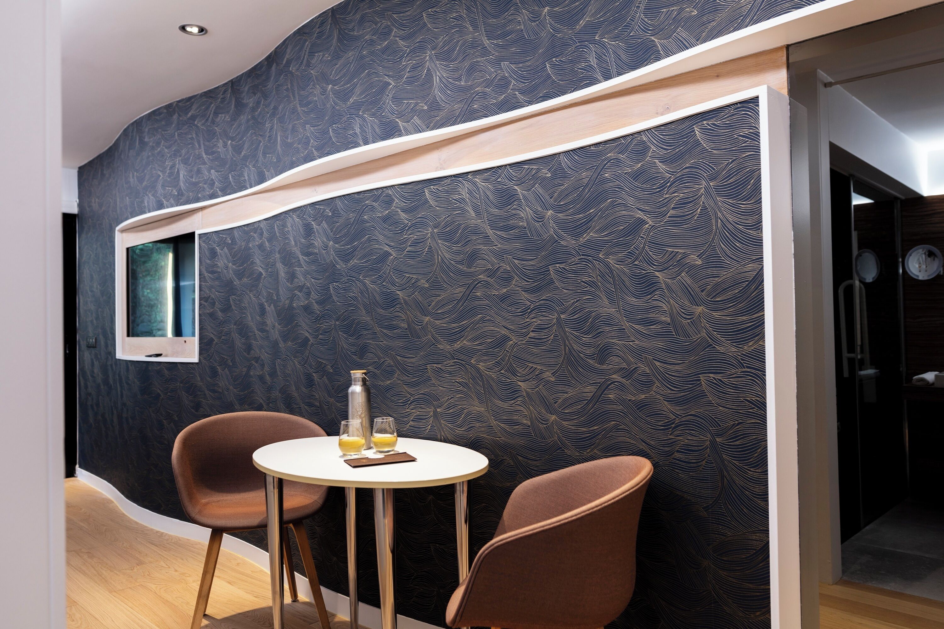 Une pièce moderne avec un mur incurvé, une table ronde, deux chaises et une petite fenêtre.