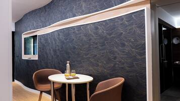 Une pièce moderne avec un mur incurvé, une table ronde, deux chaises et une petite fenêtre.