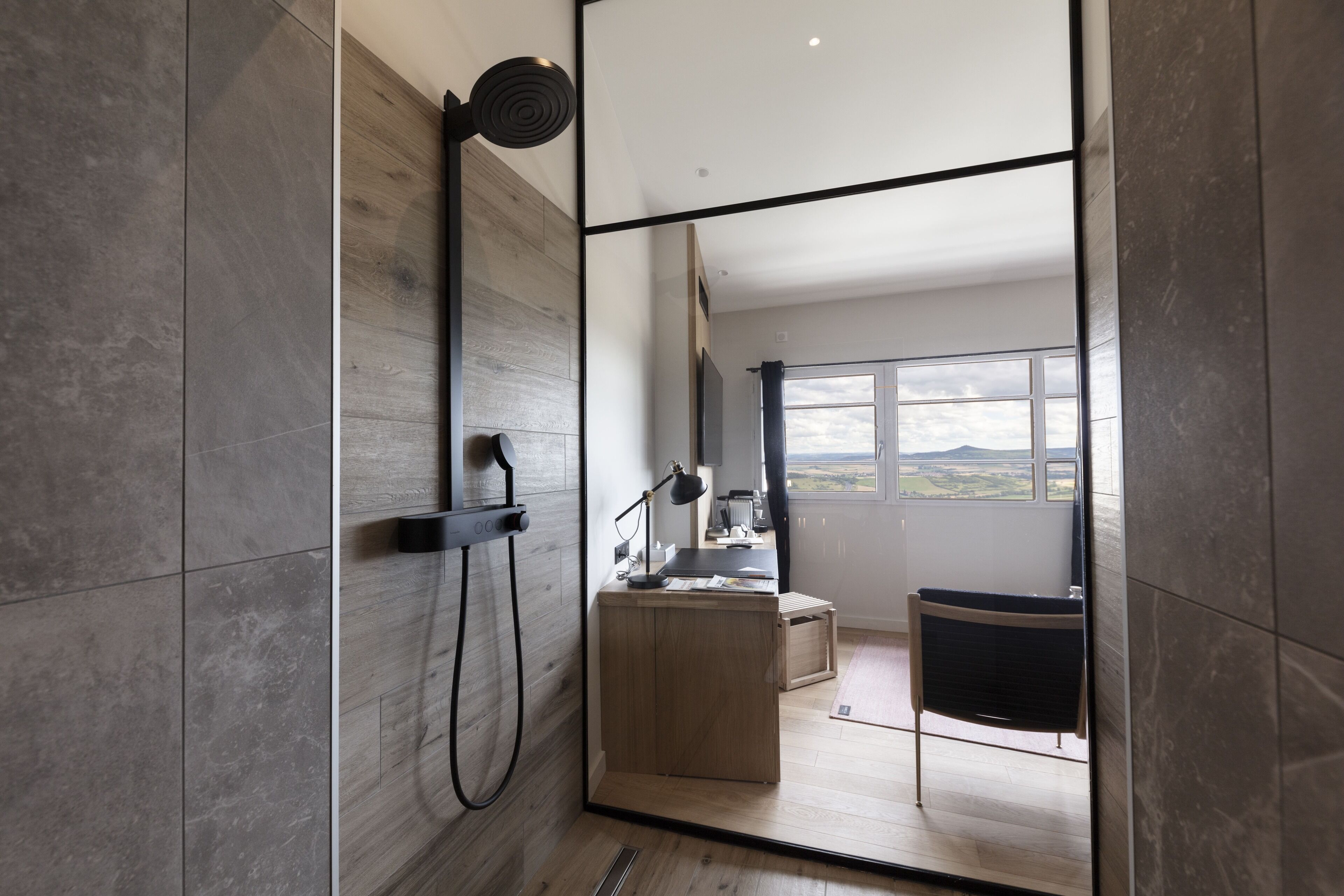 A modern bathroom with a shower, a sink, and a window offering a view of the outdoors.