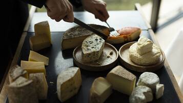 Une sélection de fromages présentés sur une planche en bois, avec une personne qui utilise un couteau et une fourchette.