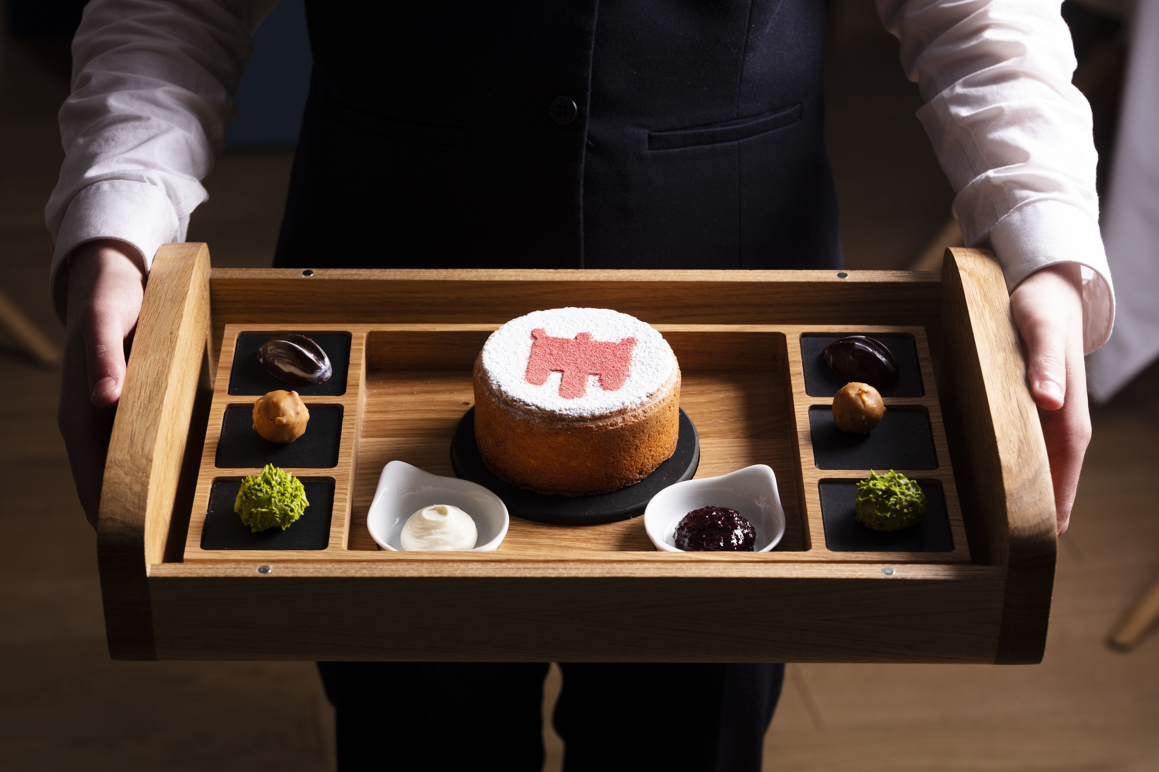 A wooden tray with a cake and various small desserts.