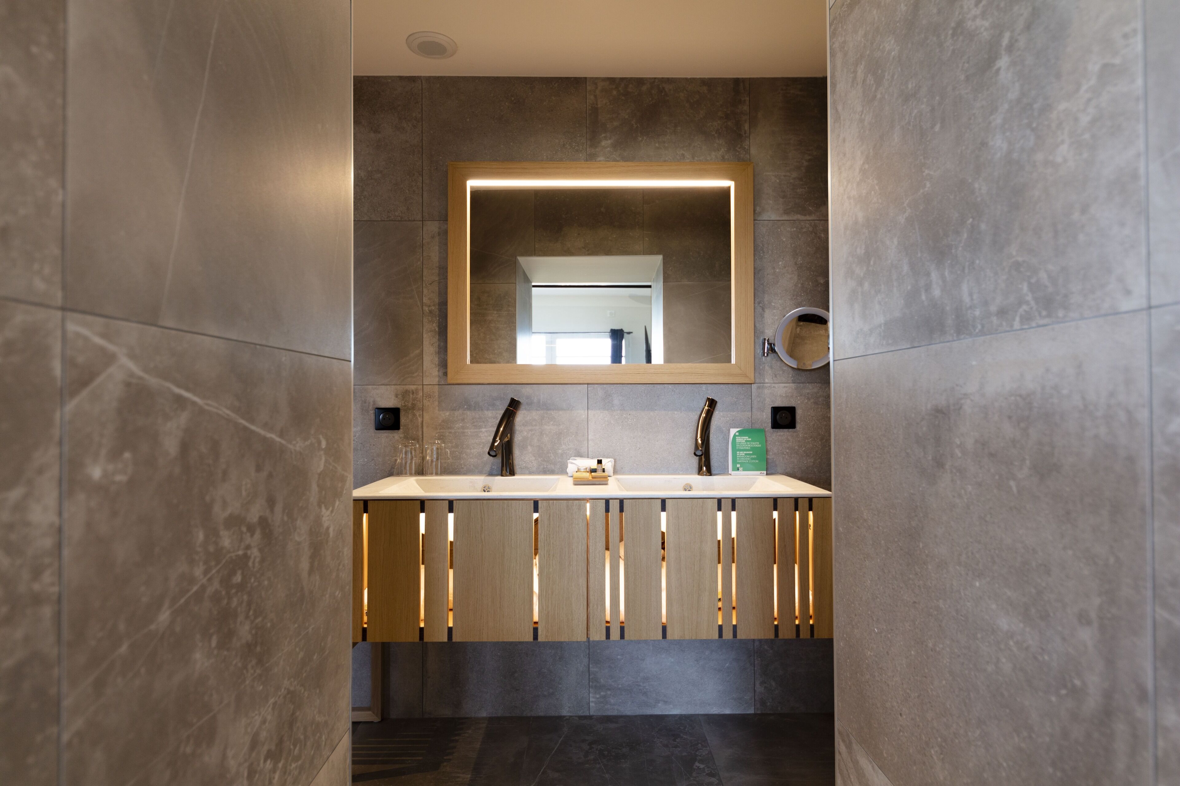 Un baño moderno con un espejo grande, un lavamanos y un inodoro.