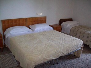 A room with two single beds, each with a wooden headboard, a bedside table, and a white blanket. - Albergo Ristorante Gualtieri (Barberino di Mugello)