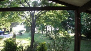 A covered outdoor area with a view of a grassy garden and trees. - Il Campetto Country House (Senigallia)