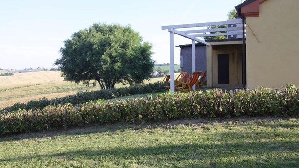 A house with a white porch and a tree in the background. - Il Campetto Country House (Senigallia)