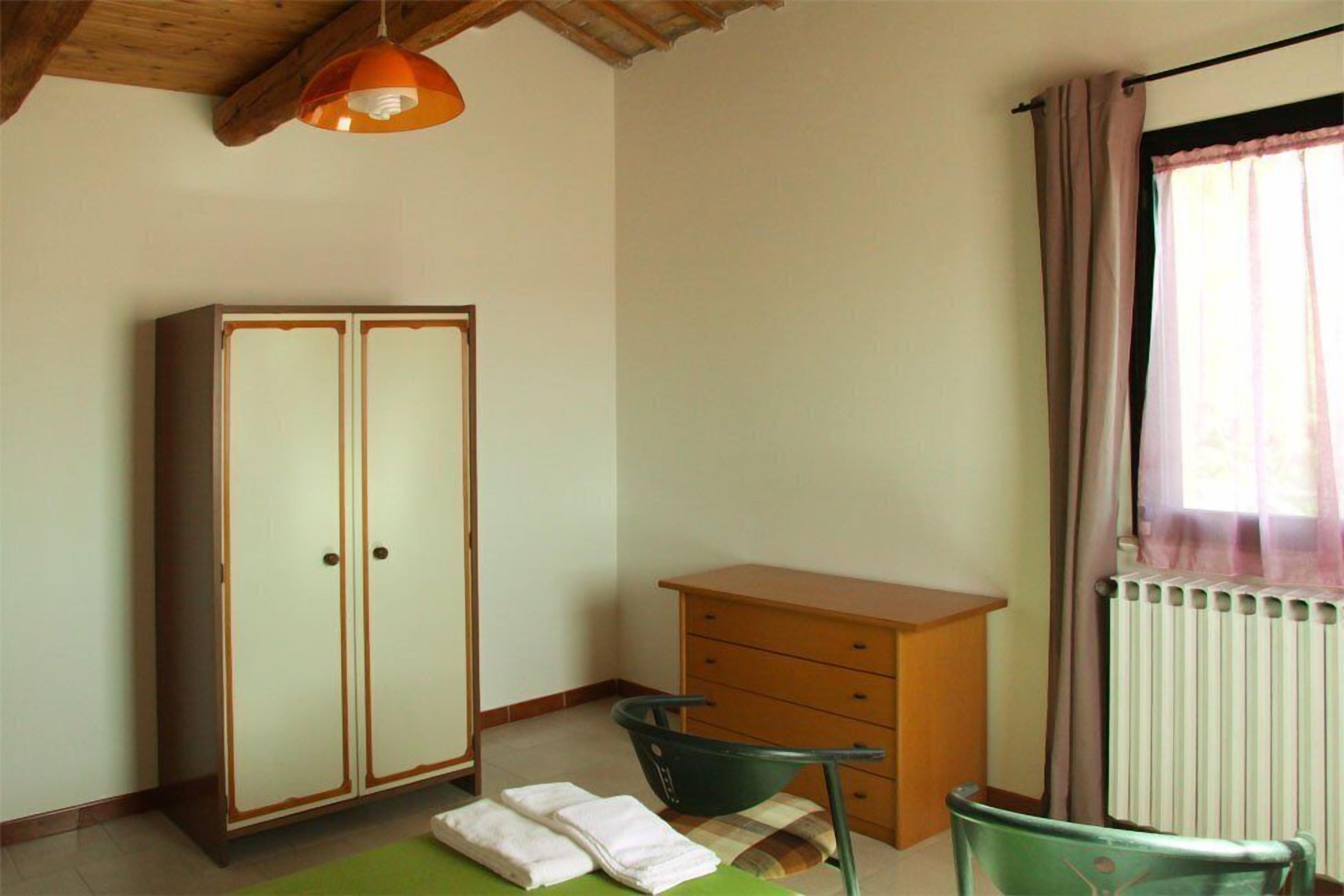 A room with a wardrobe, a desk, a chair, and a radiator.