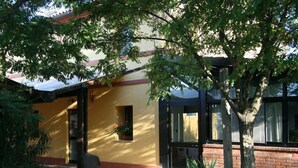 A building with a yellow facade, a brick wall, and a tree in the foreground. - Il Campetto Country House (Senigallia)