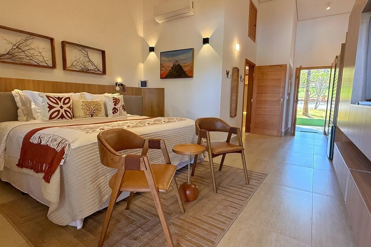 A bedroom with a bed, two chairs, a small table, and a TV.
