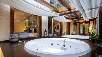 Een luxueus wellnessgedeelte met twee bubbelbaden, een grote spiegel en uitzicht op een tuin.