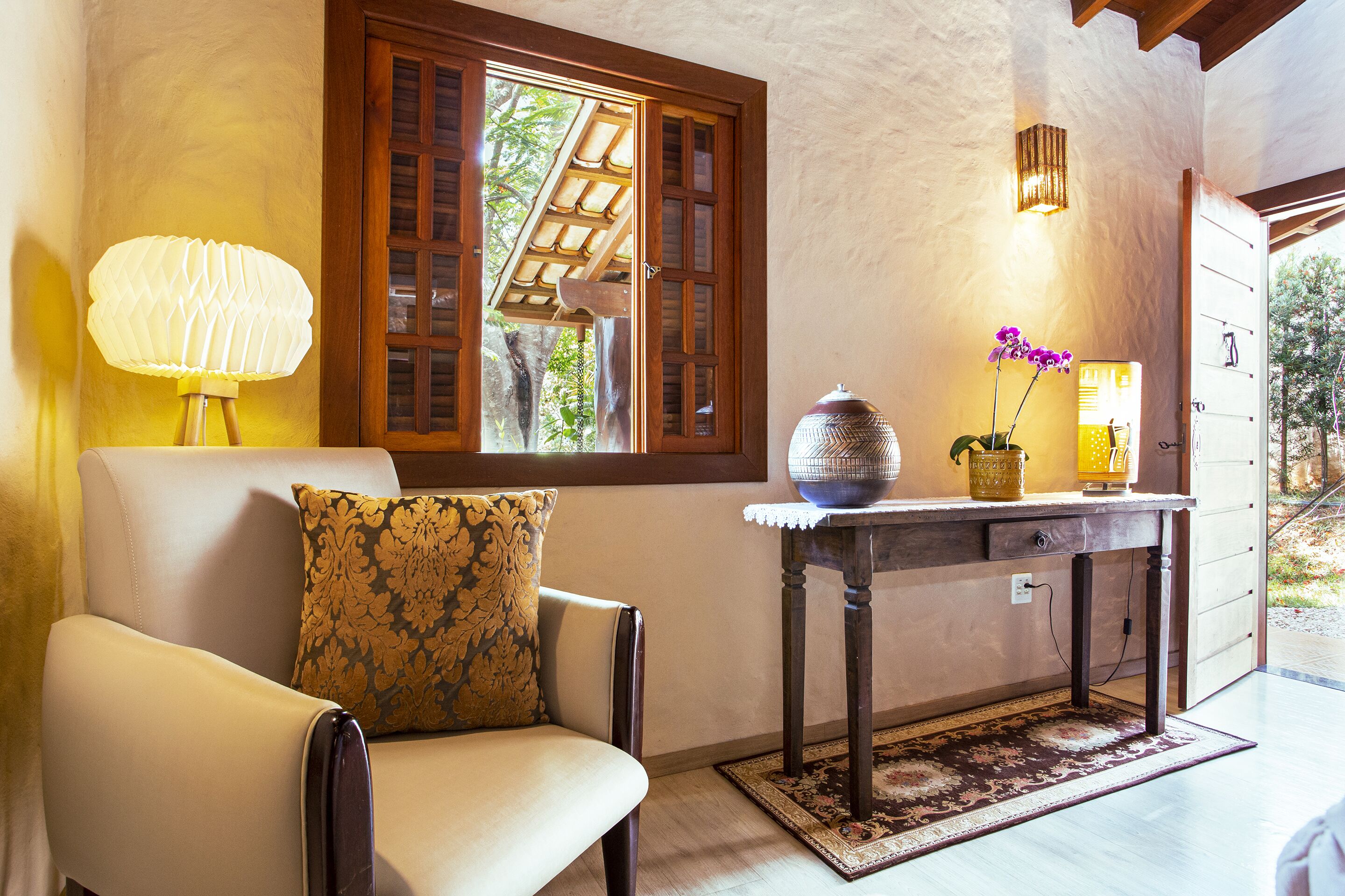 Un salon confortable avec un canapé, une table ornée d’un vase de fleurs et une lampe.