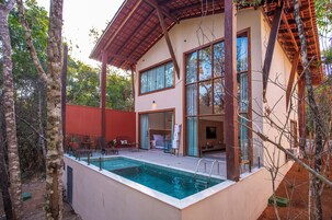 A modern house with a swimming pool, large windows, and a patio area.