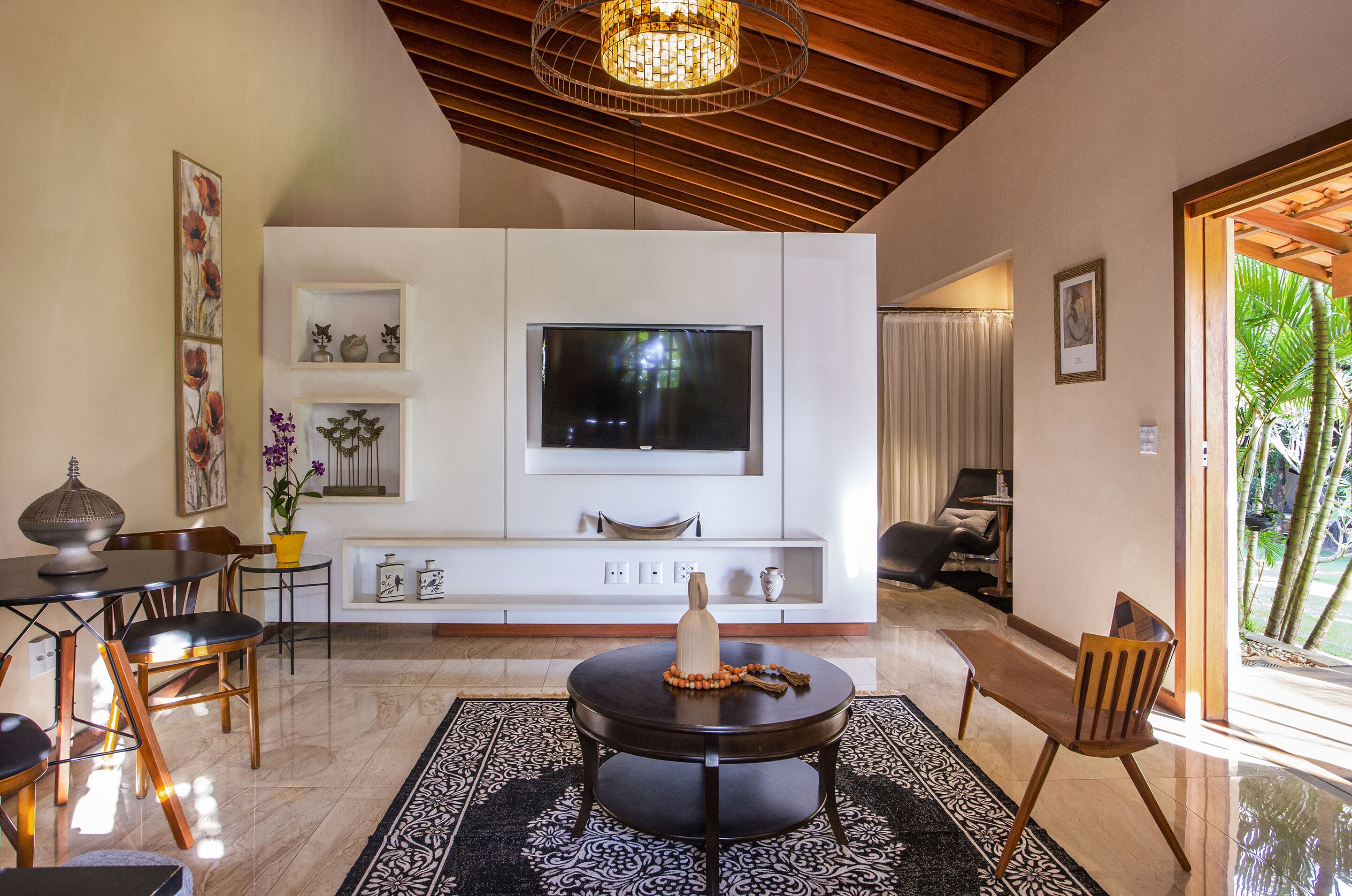Un salon moderne avec un téléviseur à écran plat, des meubles en bois et un vase décoratif posé sur une table ronde.