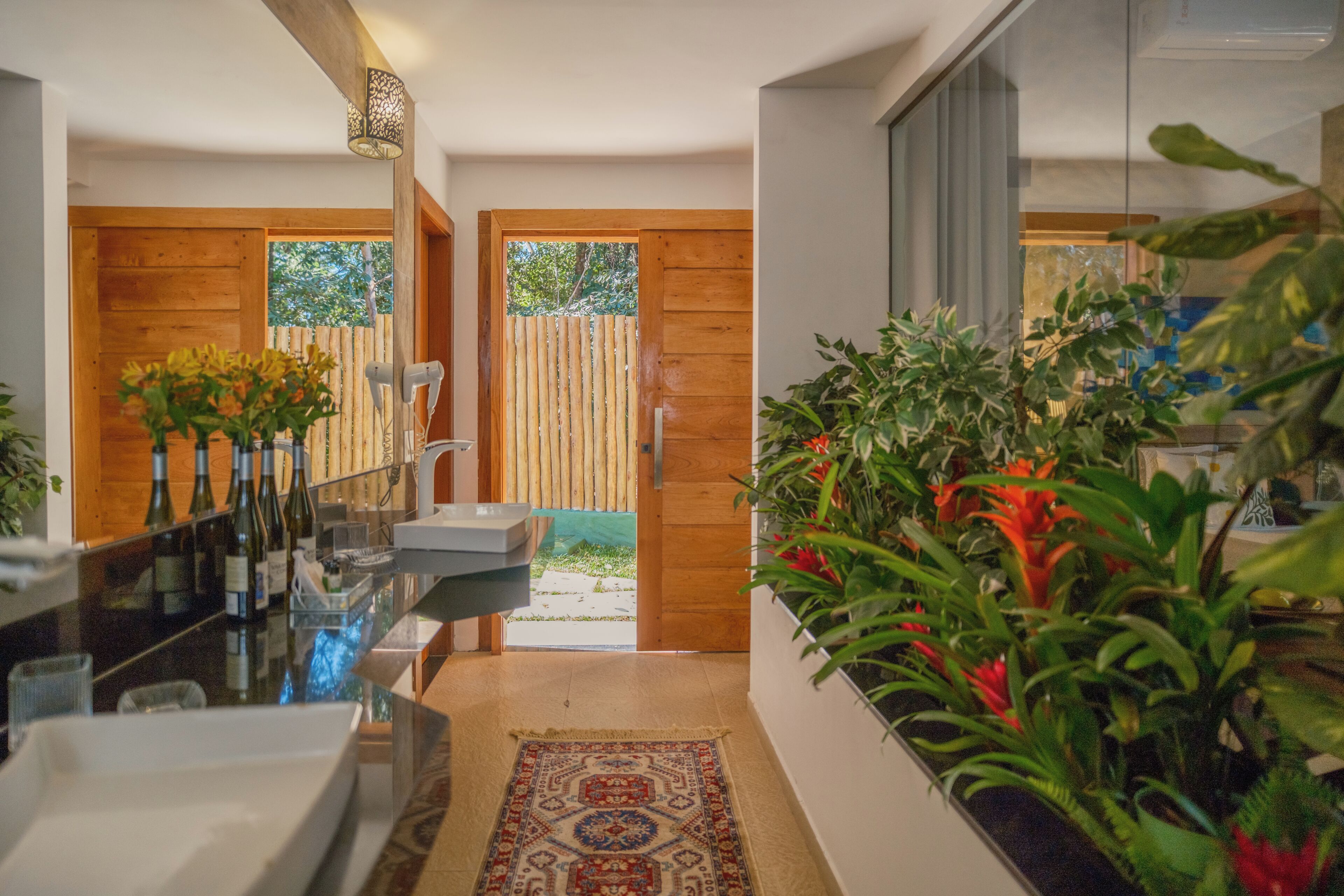 Un baño moderno con cabina de ducha de vidrio, puertas de madera y una planta a la derecha.