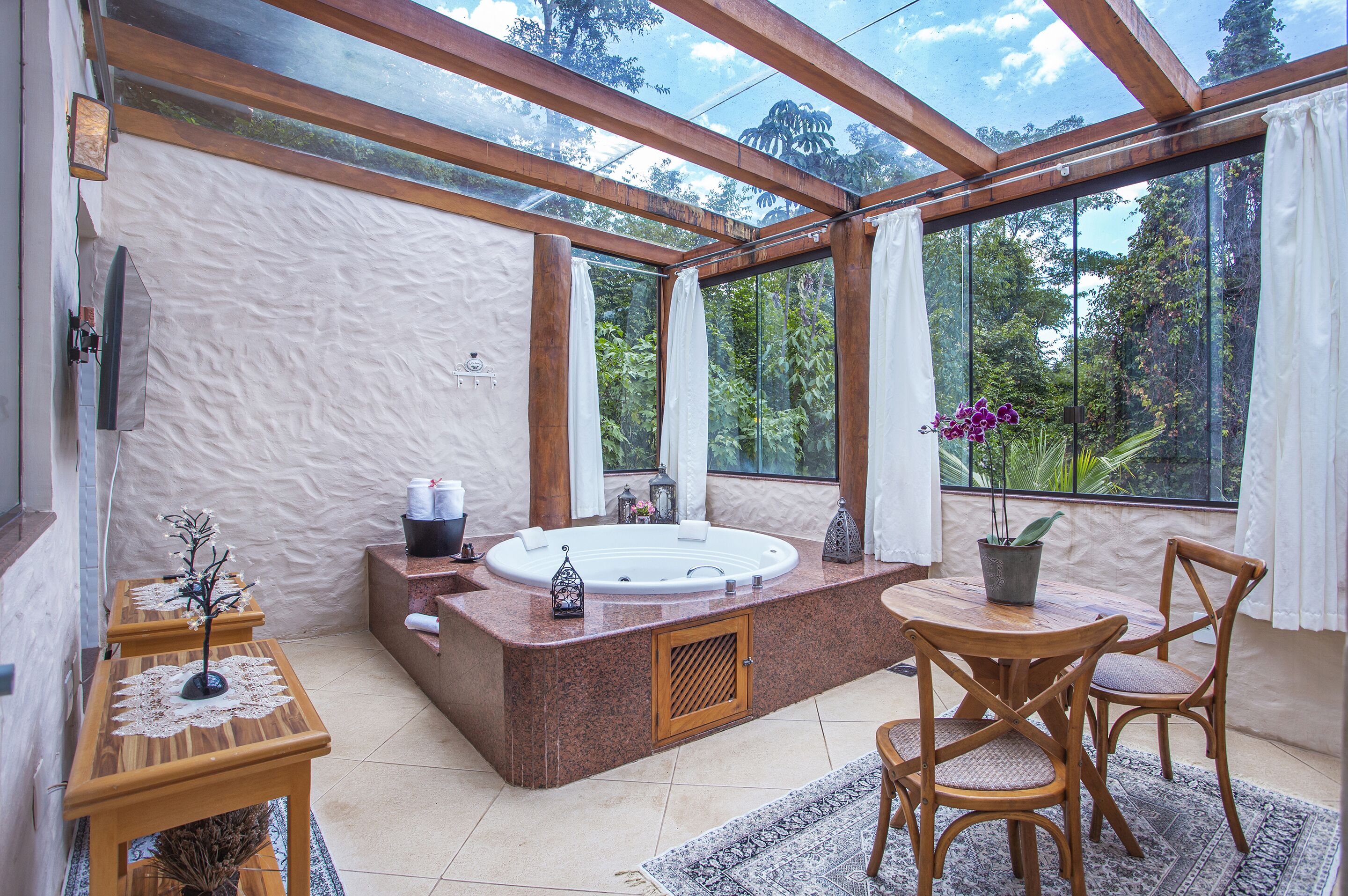 A spa area with a hot tub, wooden furniture, and large windows offering a view of the outdoors.
