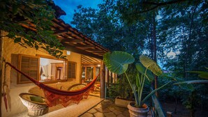 Un espacio exterior acogedor con una hamaca, una silla de mimbre y una planta en maceta.