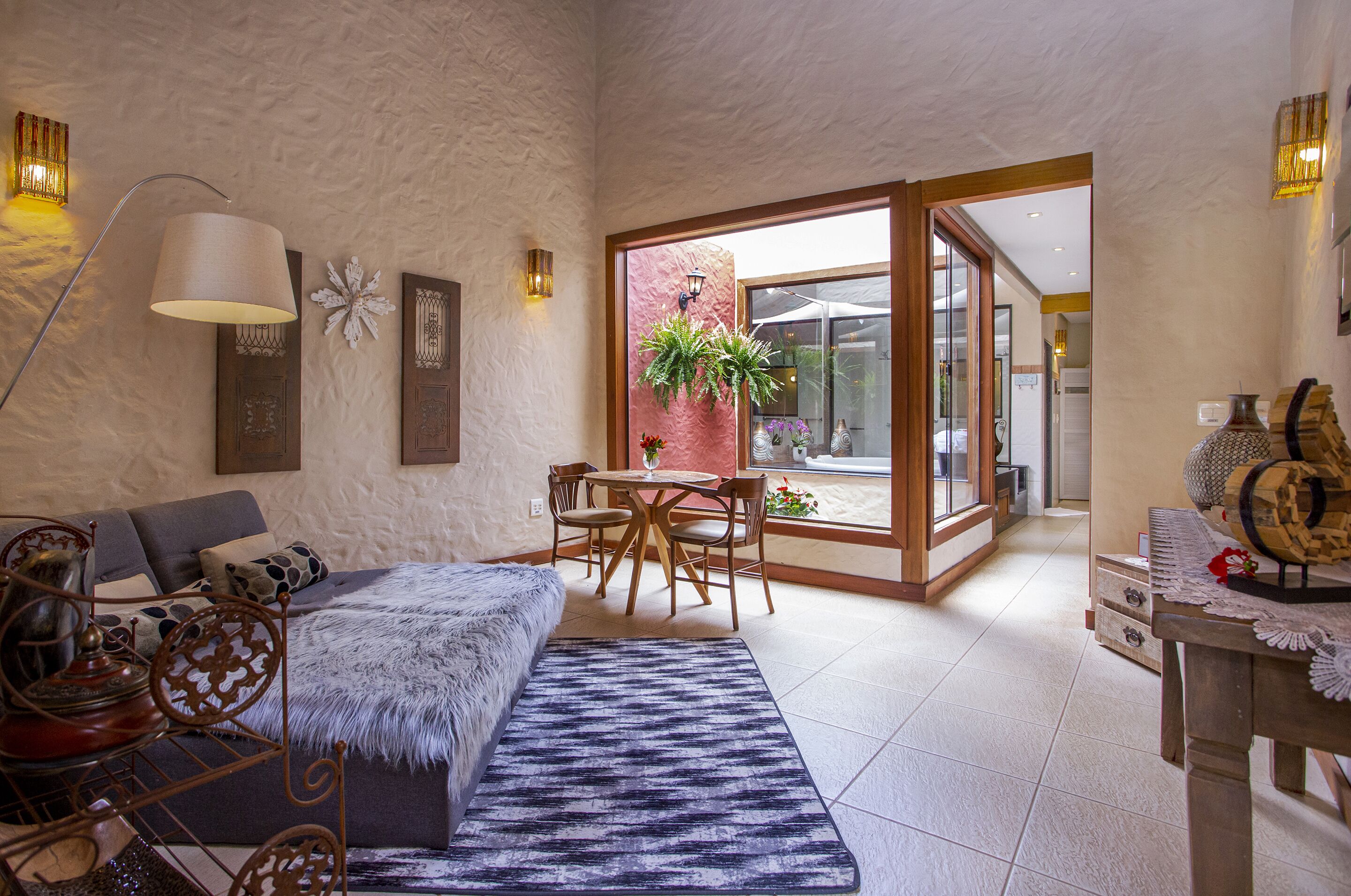 Una sala de estar acogedora con un sofá, una mesa de centro y un comedor con sillas. Hay un ventanal con vistas al exterior.