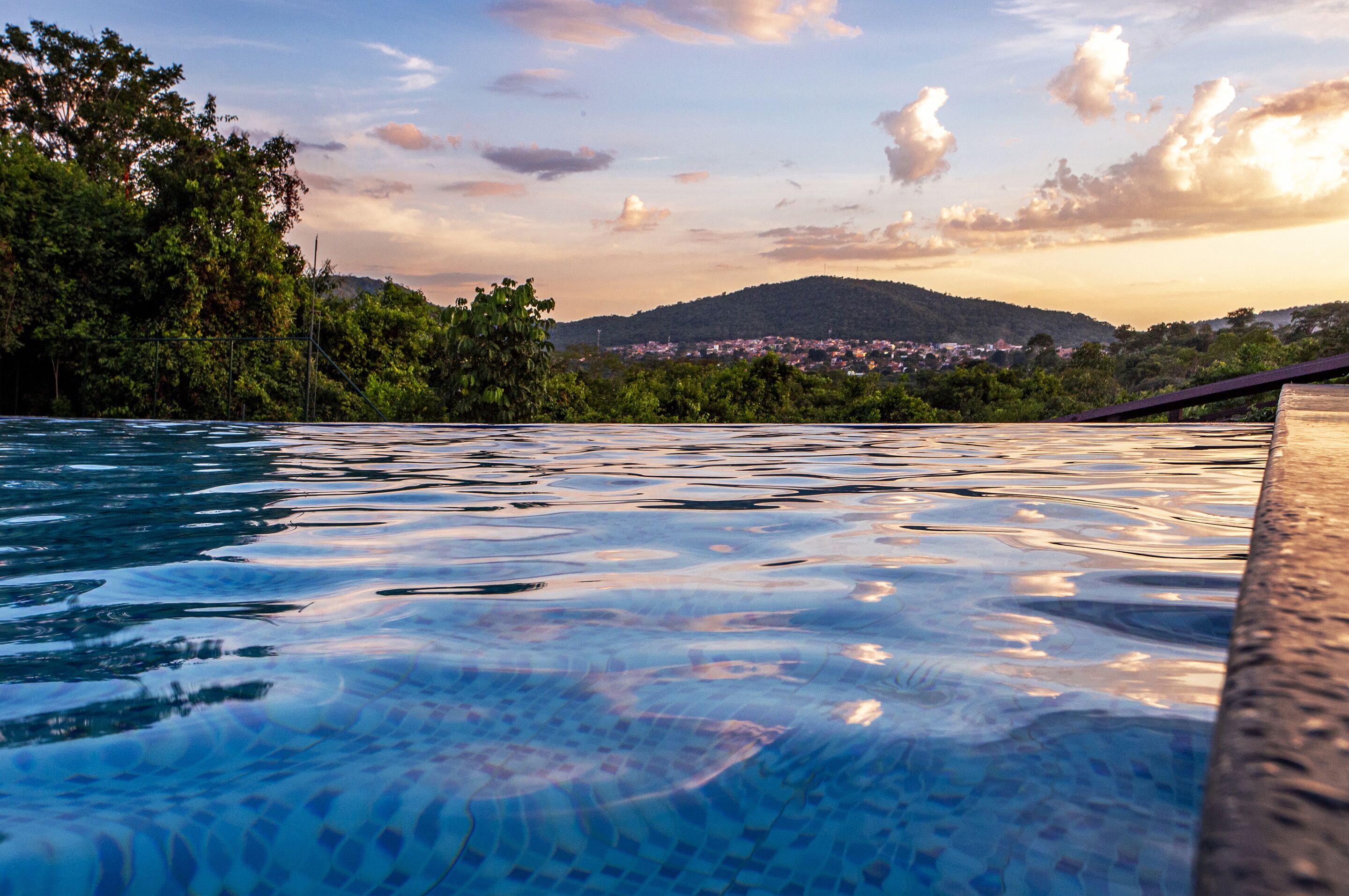 A swimming pool with a view of a town and hills in the background.
