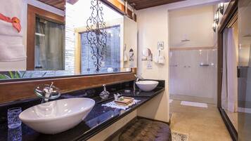 Un baño con un espejo grande, dos lavamanos, cabina de ducha de vidrio y techo de madera.