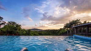 Una piscina con vistas a un paisaje montañoso y una zona cubierta con barandilla.