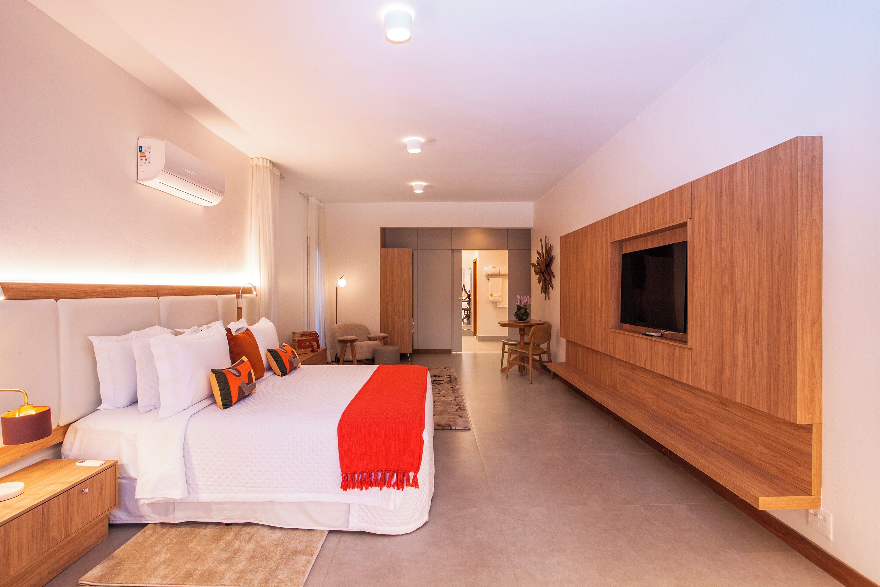 Una habitación de hotel moderna con una cama grande, un televisor montado en la pared y un diseño de paneles de madera.