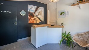 Et receptionsområde med sort væg, en træreception, et ur, et kort, en plante og en fletstol.