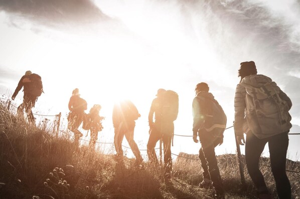 A group of people hiking in a grassy area with a clear sky.